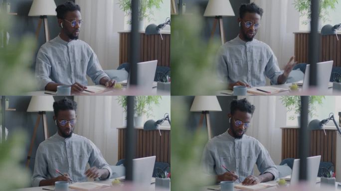 雄心勃勃的自由职业者，非裔美国人，与客户交谈，使用笔记本电脑进行在线视频通话，在家写作