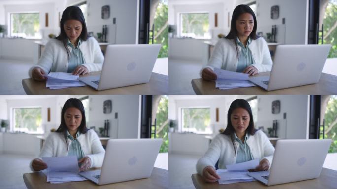 沮丧的亚洲女人，笔记本电脑和文件在金融危机，收据或开支在压力，焦虑或账单在家里。有财务方面的文书工作