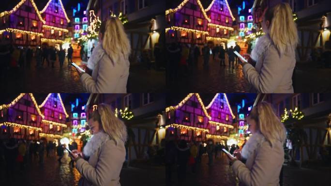 一名女子在科尔马一个热闹的圣诞市场漫步时使用着她的智能手机