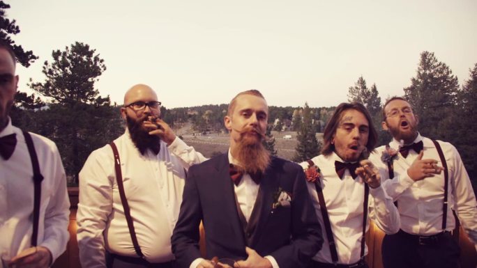 在户外举行的婚礼上，白人新郎和他的伴郎们打着领结抽烟