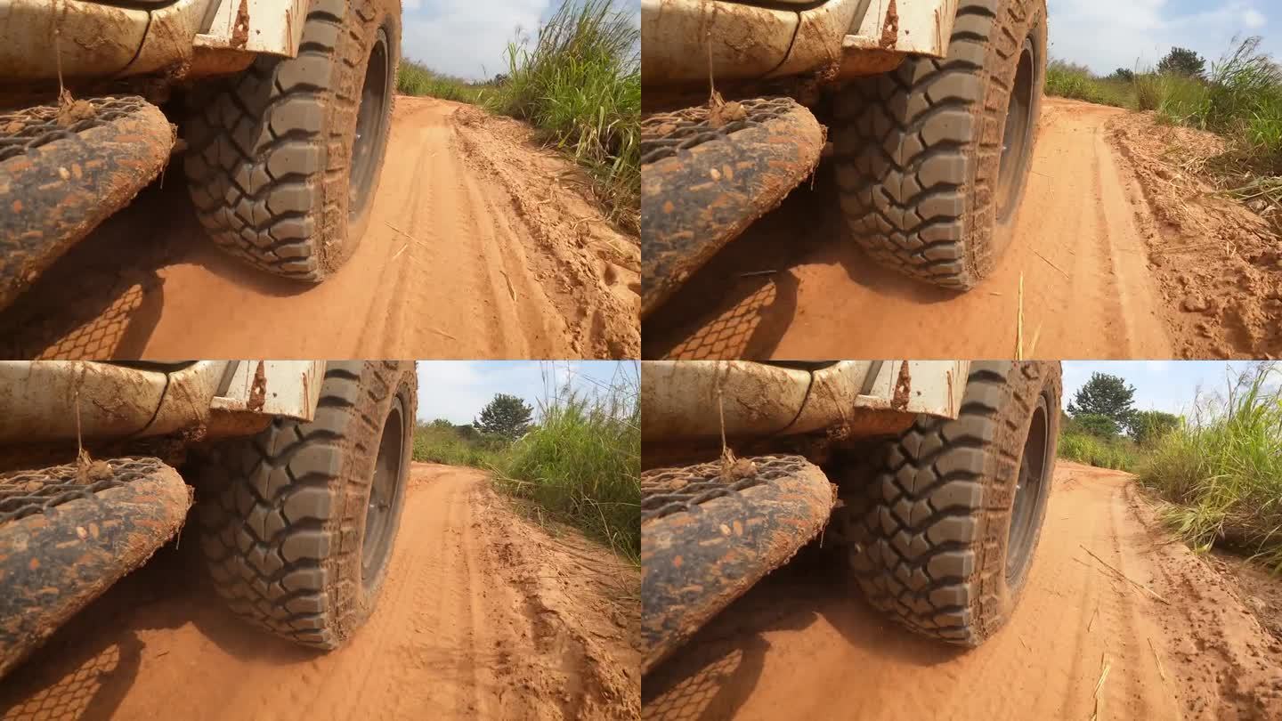 在土路上奔跑的视角。越野车的车轮行驶在尘土飞扬的肮脏道路上，湿的和干的泥。在穷乡僻壤旅行的观点