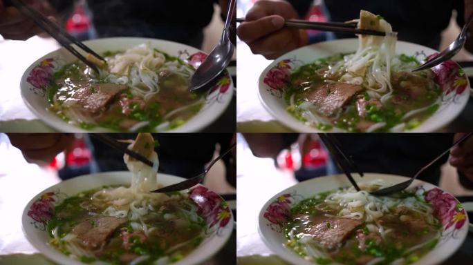 一名男子在金属桌子上用筷子和勺子吃着越南传统的Pho Bo汤、牛肉和米粉