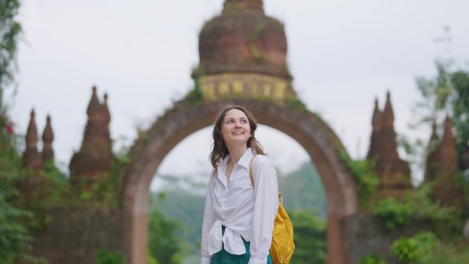 一名女子走在通往泰国丛林中一座古庙的大门附近