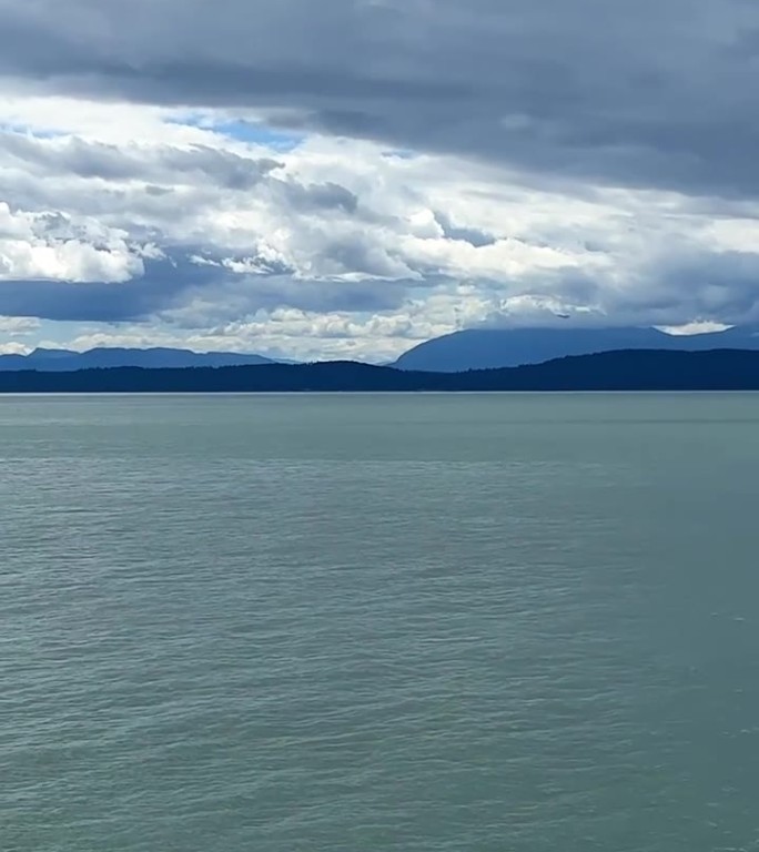 灰色银色的云在明亮的蓝色天空绿松石无色的水太平洋将图片分为两部分背景的任何标题文字或广告旅行加拿大到