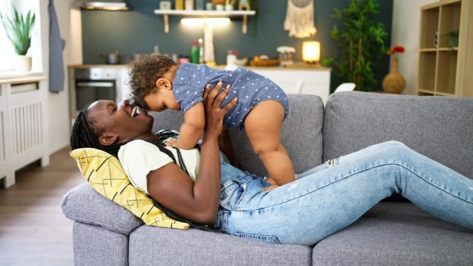 母亲和儿子黑种人躺在沙发上玩耍