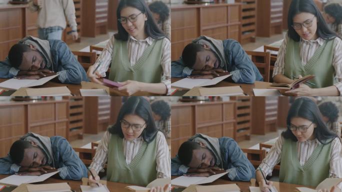 亚洲女人在大学图书馆学习，而疲惫的非洲裔美国男人懒惰的学生睡觉