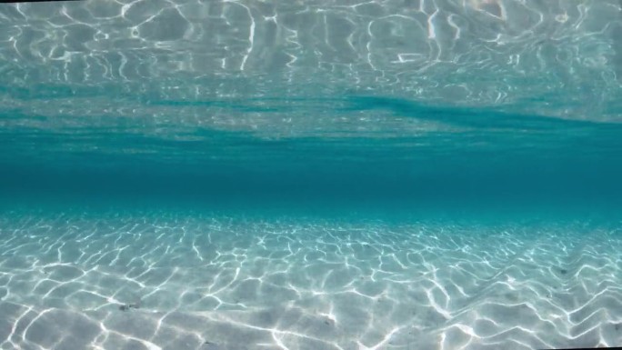 透明的海洋，沙质海底和海浪在巴哈马群岛。水下视图