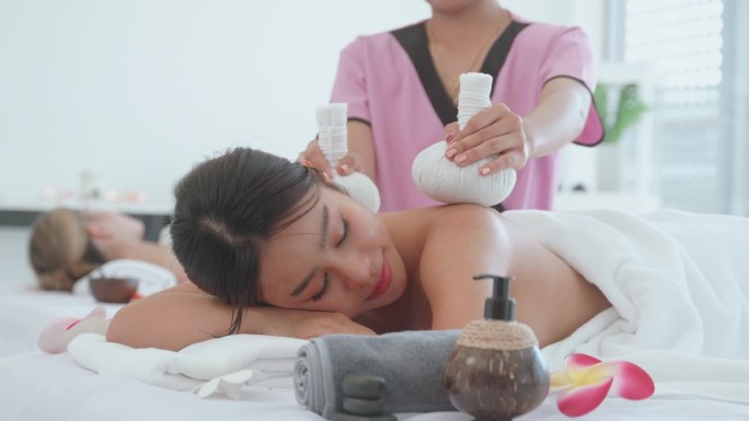 女子水疗与泰国草药球热敷按摩。