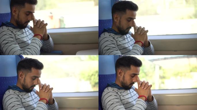 一个印度年轻人坐在火车上看着窗外的风景。