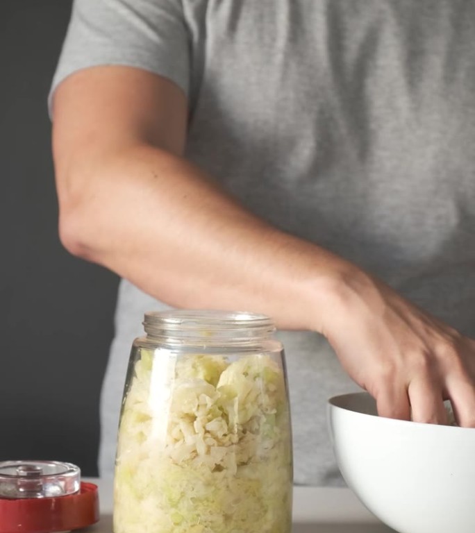 男子将卷心菜放入发酵罐中准备酸菜。