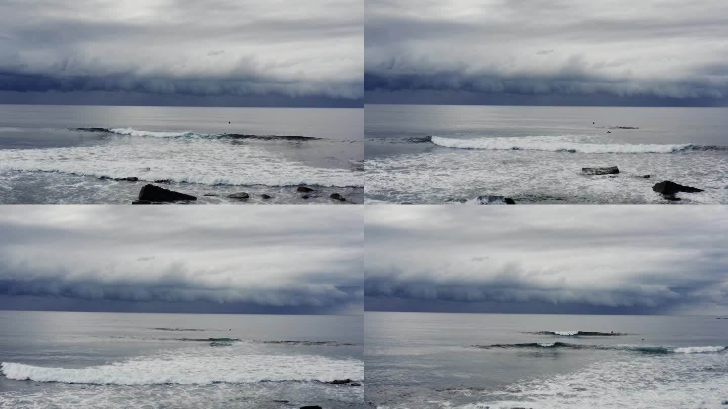 广阔的航拍画面，海浪滚滚涌向海岸，黑暗，戏剧性的风暴云在银色的海洋上移动