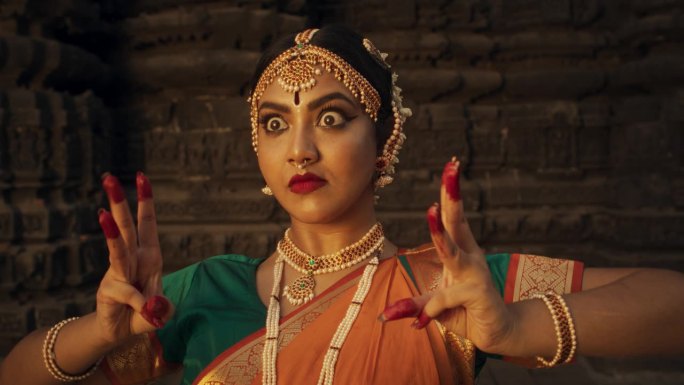 一个印度女舞者的特写，用民俗舞蹈展示象征性的手势和富有表情的脸，讲述一个故事。穿着传统纱丽的女孩展示