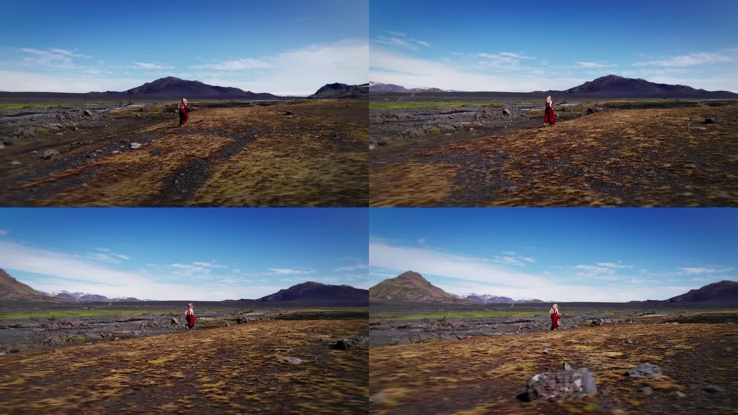 一个女孩穿着红裙子跑过冰岛高地。的乐趣。