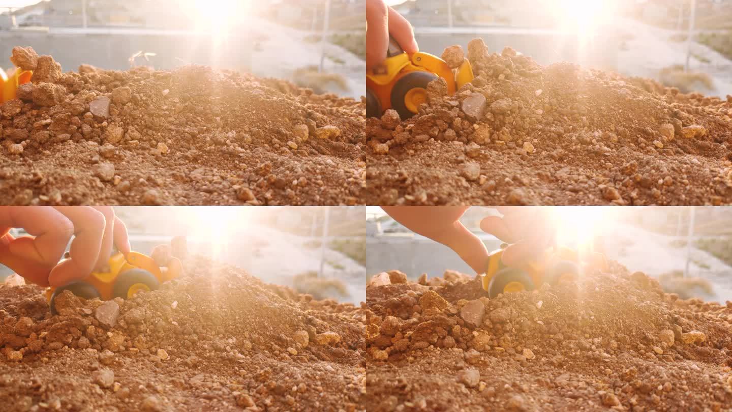 在阳光下用手在地上玩玩具挖掘机