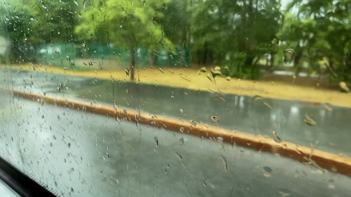汽车西面玻璃窗的特写，雨点落在背景中。