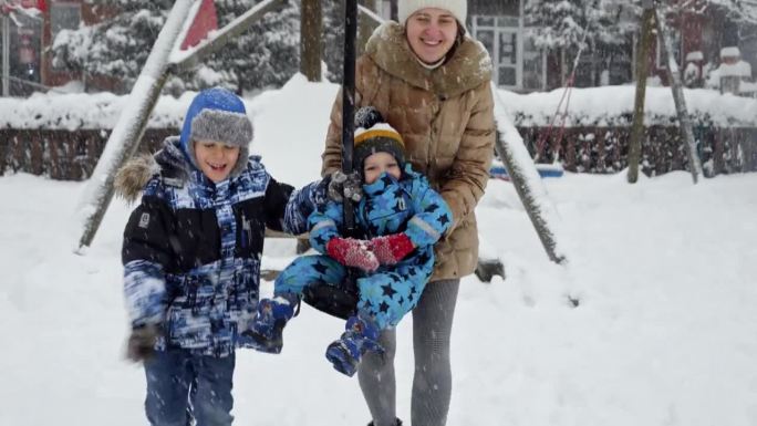 在公园的操场上，一家人开心地笑着玩雪。寒假里的欢乐，家人一起玩耍，大雪里的活动