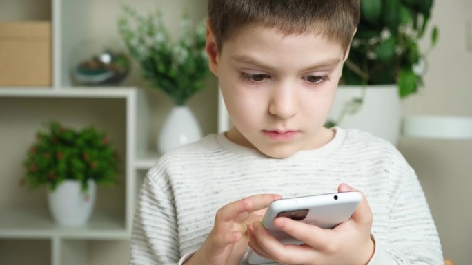 孩子使用手机，手里拿着智能手机，看着屏幕。屏幕时间，家长控制