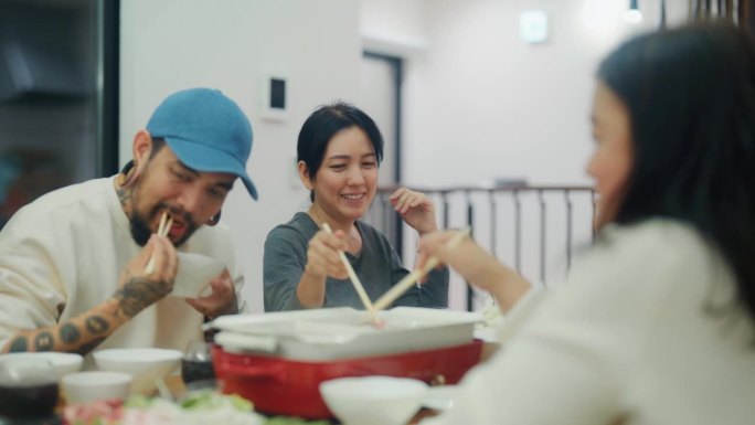 一群亚洲男人和女人在日本度假时在公寓里一起庆祝和吃饭。大旅行，小预算