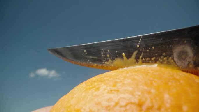 我正对着蓝天用刀切橘子。宏观，慢动作。