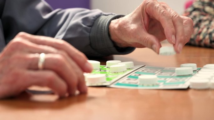 一个老人在养老院玩宾果游戏的特写。休闲游戏，支持，辅助生活和退休。高品质4k画面