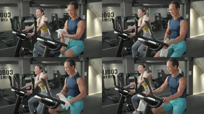 运动员65岁亚洲老年男性在现代健身房里与健身朋友进行改善心血管系统的自行车运动，中年亚洲女性穿着黄色