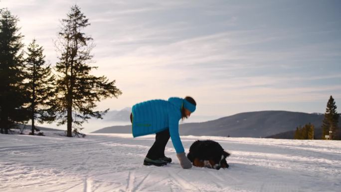 一个女人和她的狗一起在雪地里徒步旅行