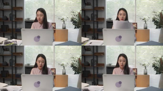 年轻时尚的韩国女性专业人士在她舒适的家庭办公室沉浸在笔记本电脑工作中，项目经理用建筑的眼光研究现代设