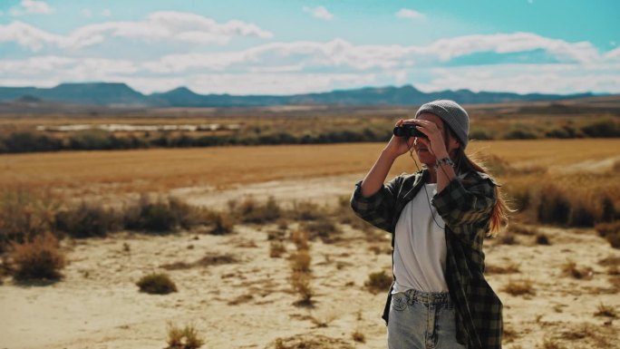 一名妇女用双筒望远镜观察摩洛哥的沙漠和落基山脉