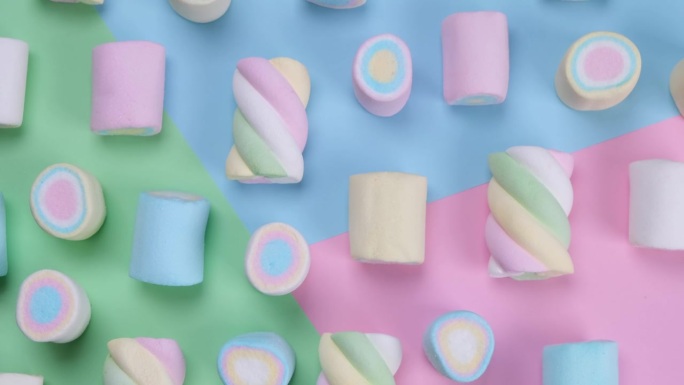 五彩缤纷的背景上旋转五颜六色的耐嚼棉花糖，一个生日，节日，有趣的概念，时尚甜蜜的背景