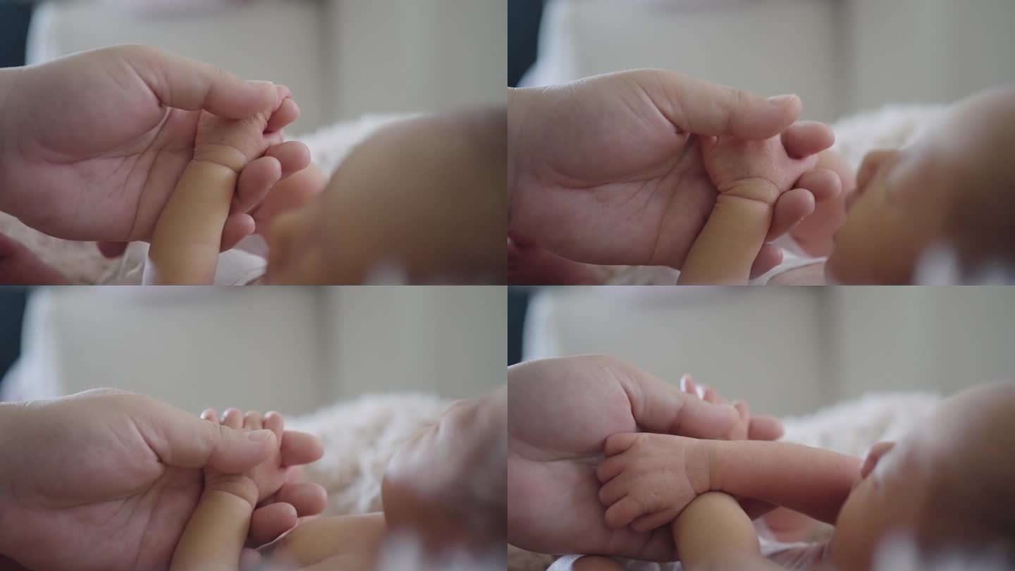 母亲的手握着，抚摸着新生婴儿的小手