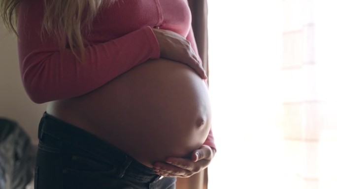 女人抚摸和抚摸她美丽的怀孕肚子，表达她对孩子的爱和感情，漂亮女人的快乐产前期，怀孕肚子的概念
