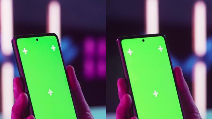 垂直屏幕:时髦的人拿着智能手机，看着绿色模拟显示屏的屏幕。视频模板与数字营销，视频游戏，应用程序，网
