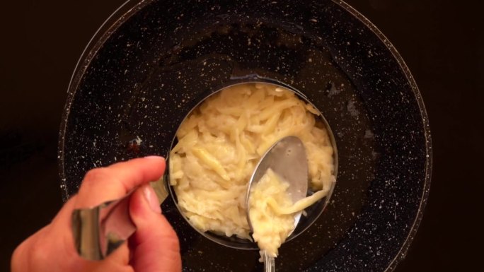把生土豆泥放在圆模里的煎锅里