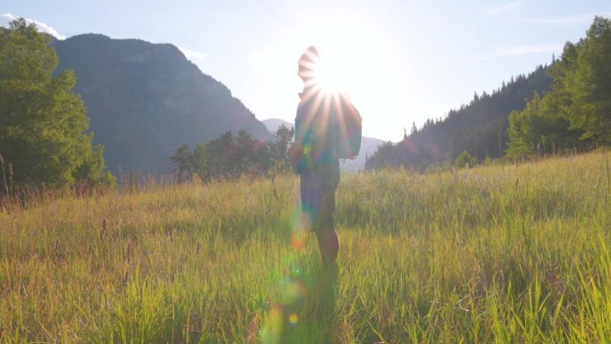 资深男性徒步旅行者探索高山草地，用智能手机拍照