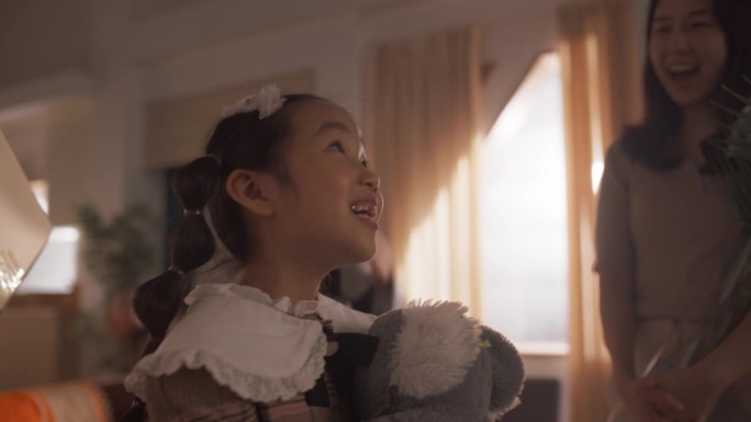 幸福的韩国小家庭为他们的新家感到兴奋:可爱的小女孩抱着她的泰迪熊蹦蹦跳跳，惊讶于她的新家是多么宽敞和