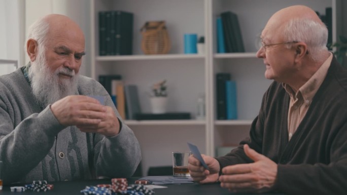 两个老年男性朋友在养老院打扑克，休闲时间