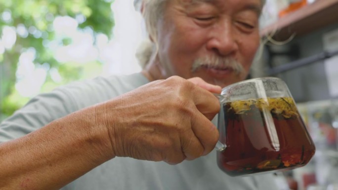 亚洲老人沏菊花水，和他的孙子开心地跳舞。