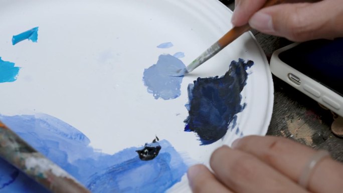 特写小笔刷正在使用混合颜色在一起，通过使用原色混合得到想要的颜色，使用笔刷混合它们在一起改变相同的颜
