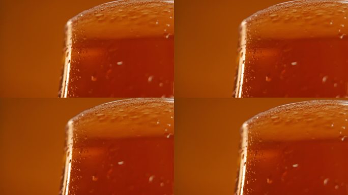 特写部分的啤酒杯与饮料在橙色的背景在右边。清凉酒精饮料广告。