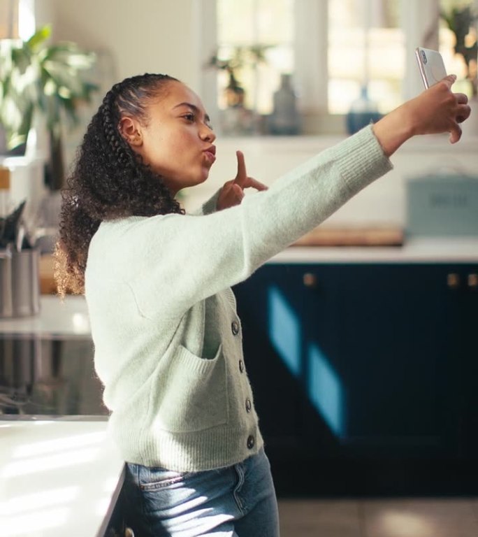 十几岁的女孩在家里摆姿势自拍的垂直视频上传到手机社交媒体上