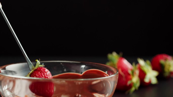 融化巧克力中的草莓特写，融化巧克力棒做火锅。把浆果放进巧克力慕斯。专业厨师烹饪蛋糕甜点。