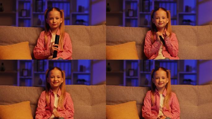 晚上，开朗的女孩坐在沙发上，用遥控器打开电视。女孩很高兴，她最喜欢的卡通节目正在播出，她举起手，喜欢