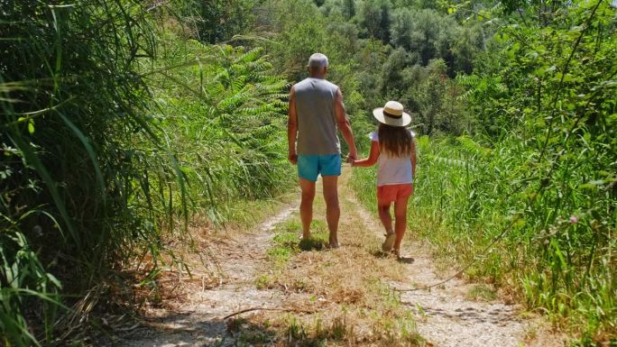 暑假期间，白人女孩和爷爷在意大利村庄的乡村路上散步