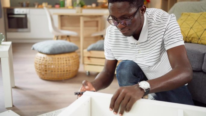 专心的非洲裔美国人在公寓里组装新家具