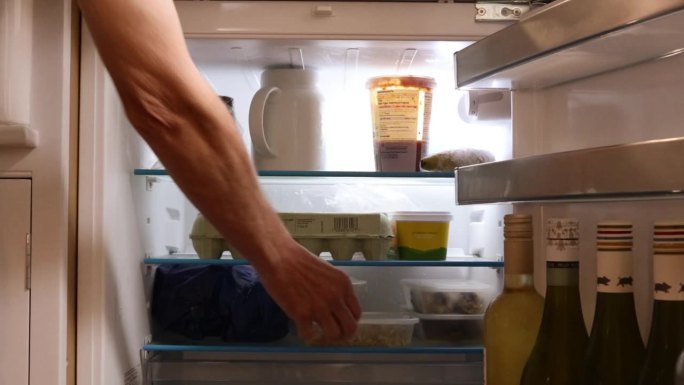 男人打开和关闭冰箱拿食物