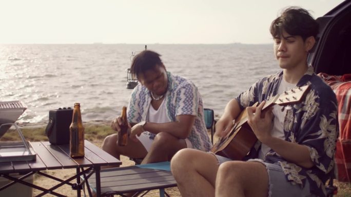 一群朋友在海边露营时聊天、唱歌、跳舞，在海滩上享受假期旅行