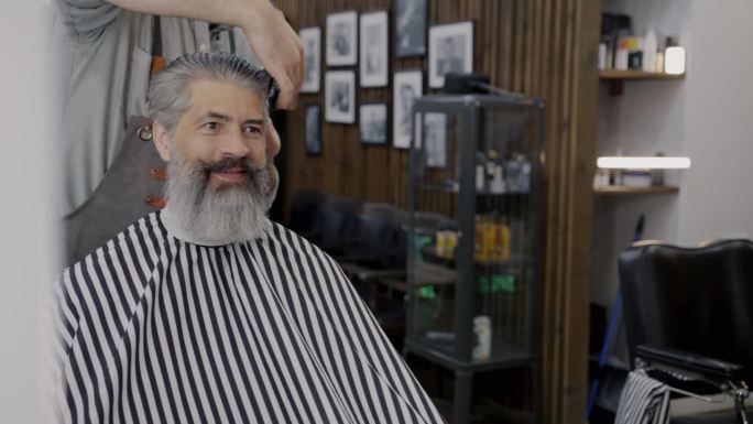 理发师在沙龙里梳头和剪发时，顾客微笑的照片