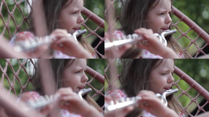 年轻女孩在秋千上演奏横贯长笛