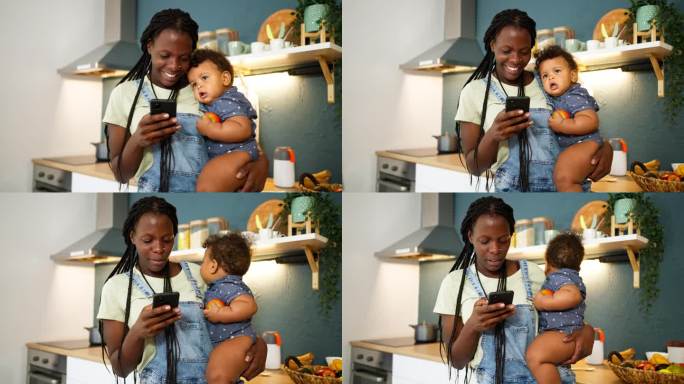 黑人母亲抱着儿子在厨房用手机