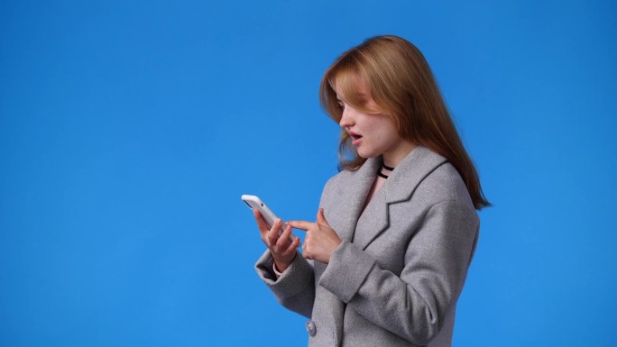 一个女孩用手机的4k视频，蓝色背景。
